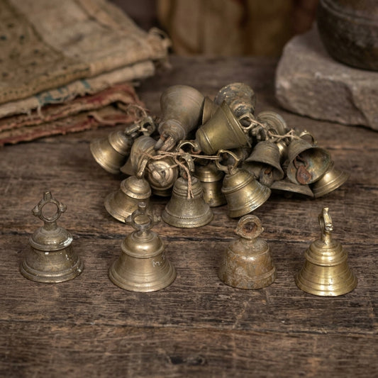 Close-up of vintage brass bell RM-72942 from India highlighting detailed engravings and patina in soft rustic lighting.